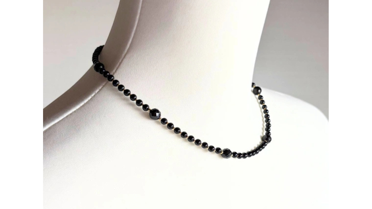 小粒のオニキスにカットオニキスをアクセントにした黒いネックレス。首元をすっきり見せるシンプルデザイン。