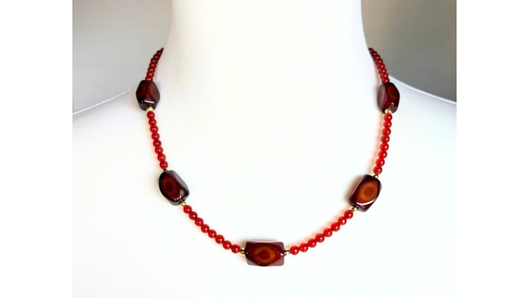 縞模様の赤めのうをポイントに配したネックレスの着用イメージ。落ち着いた赤色が首元を華やかに見せる大人のデザイン。